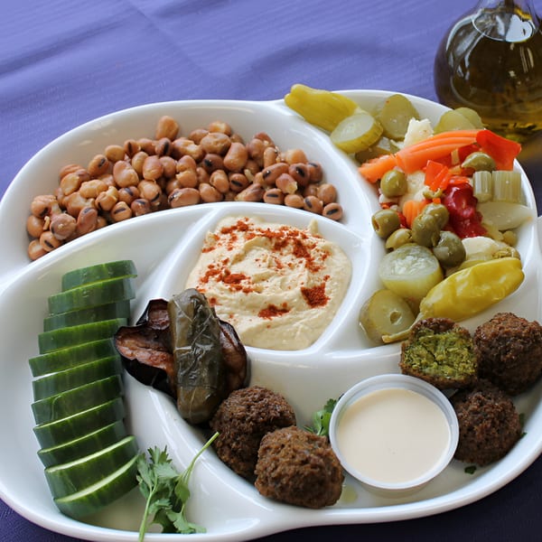 A Pita Pocket Eatery platter with falafel, hummus, cucumbers, pickled vegetables, and fava beans.