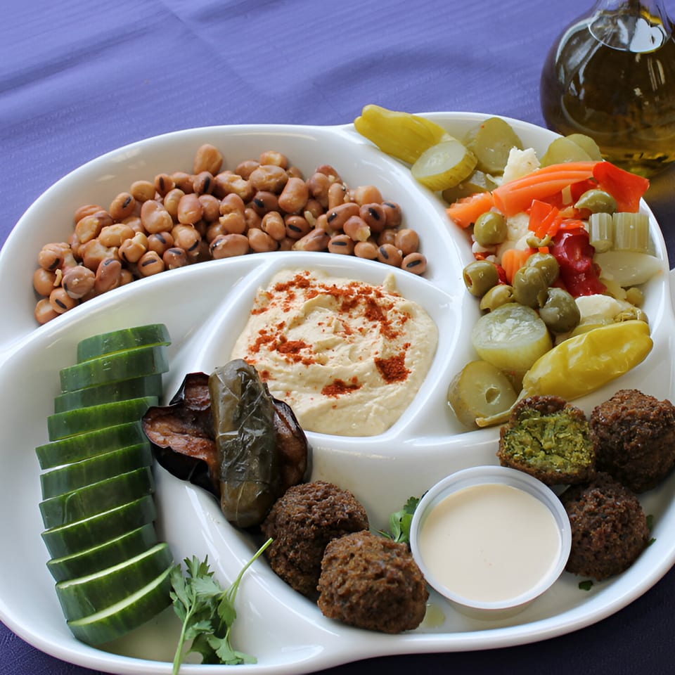 A Pita Pocket Eatery platter with falafel, hummus, cucumbers, pickled vegetables, and fava beans.