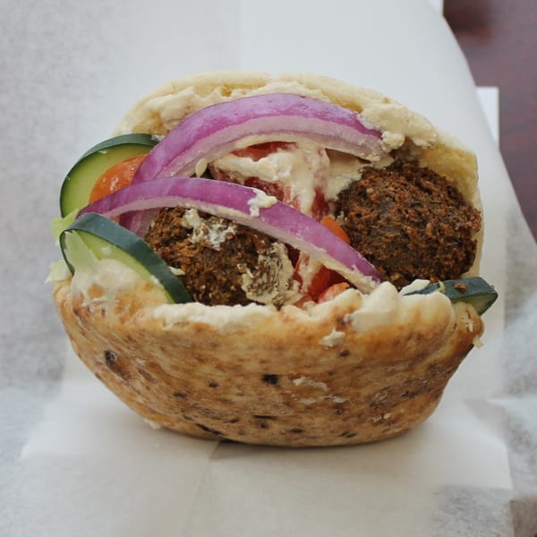 A Pita Pocket Eatery falafel pita, filled with falafel, red onions, cucumbers, tomatoes, and tahini sauce.