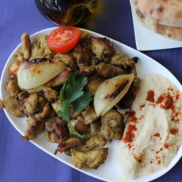 Pita Pocket Eatery's chicken shawarma plate with hummus, grilled onions, tomato, parsley, and pita bread.