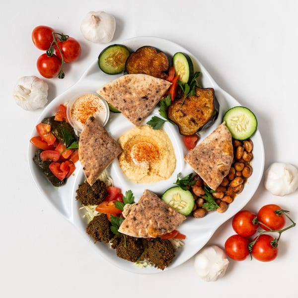 Overhead view of a Pita Pocket Eatery platter with hummus, falafel, stuffed grape leaves, and pita bread.